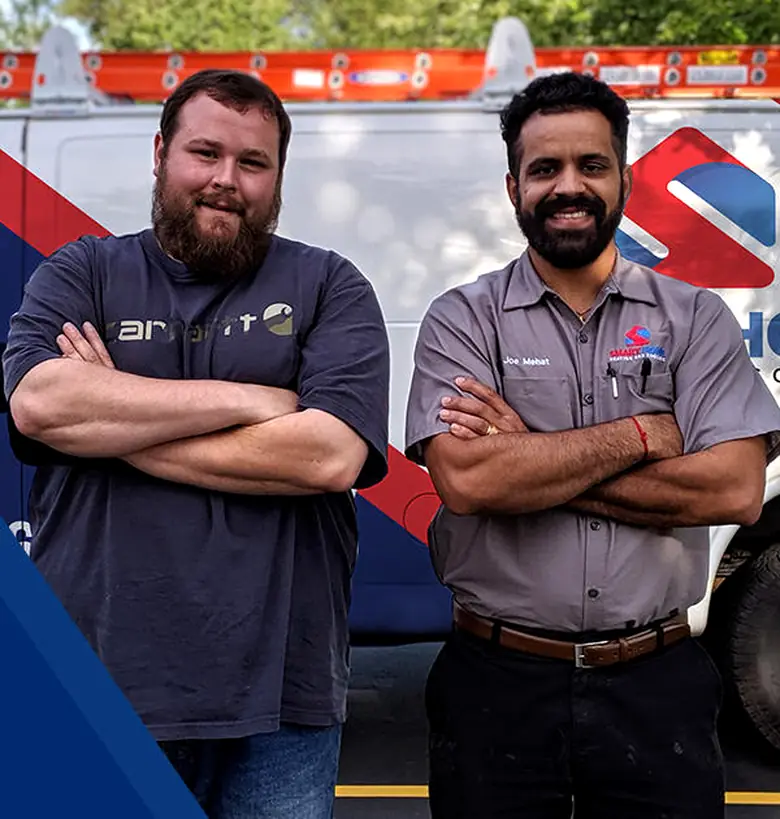 Two technicians, arms crossed, in front of their service van