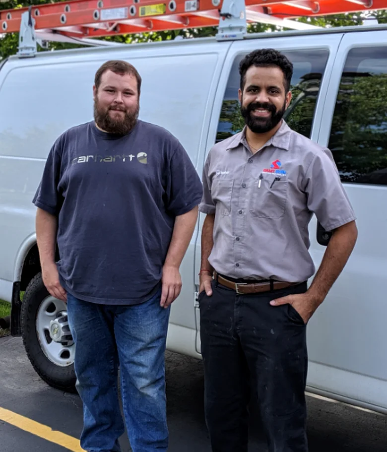 The two technicians standing by their van